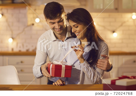 Young pretty woman unpacking holiday gift from her loving boyfriend or husband Young pretty woman unpacking holiday gift from her loving boyfriend or husband 72024768