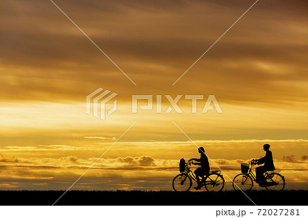 夕陽を背景に自転車通学する男女のシルエット 夕陽を背景に自転車通学する男女のシルエット 72027281
