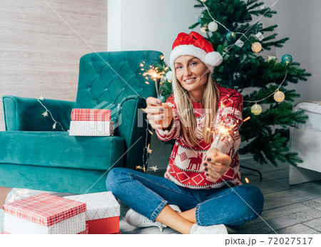 woman in santa hat with sparklers under the tree woman in santa hat with sparklers under the tree 72027517