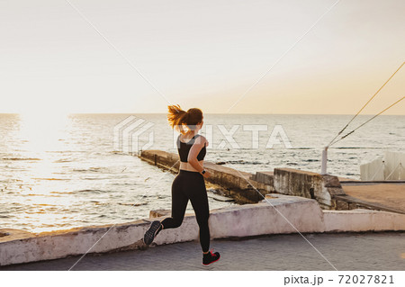 Young woman is running at the seafront 72027821