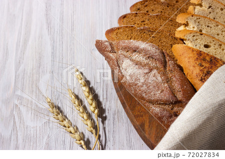 Slices of fresh homemade baguettes with whole grain on wooden board. White wooden background. Top view. 72027834