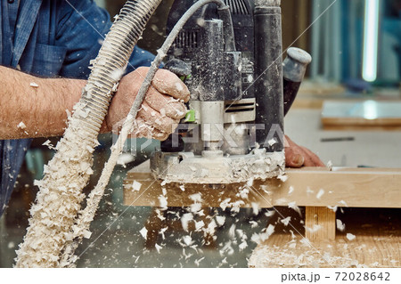 Carpenter with hand electric router machine at work. Milling process of acrylic kitchen countertop 72028642