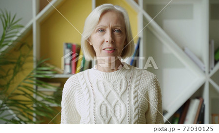 Smiling middle aged mature grey haired woman looking at camera, happy old lady posing at home indoor 72030125