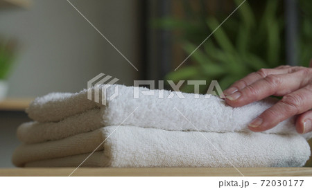 Old woman touches a fresh white towel Old woman touches a fresh white towel 72030177