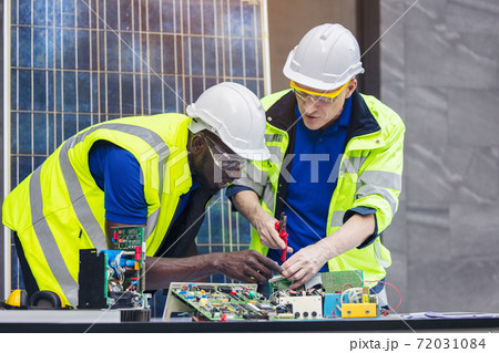 Engineer working repairing electric panel with solar panels background, Concept teamwork or training of renewable. 72031084