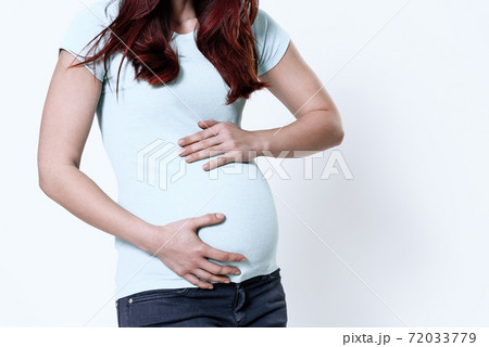 A girl with bloating is standing on a white. A girl with bloating is standing on a white. 72033779