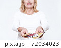 Woman shows pills to camera with outstretched hand 72034023