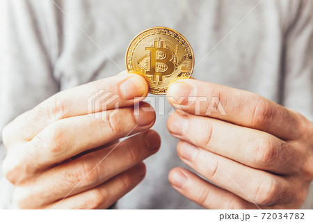 Man hand holding cryptocurrency golden bitcoin coin. Electronic virtual money for web banking and international network payment. Symbol of crypto virtual currency. Mining concept. 72034782