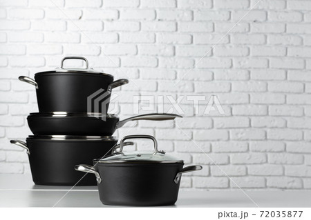 Black kitchenware on table against white brick wall 72035877