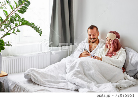 caucasian married couple have rest with smartphone on bed 72035951
