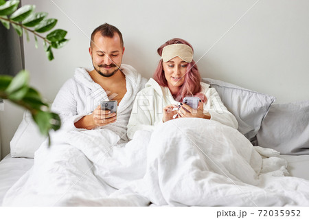 caucasian married couple have rest with smartphone on bed 72035952