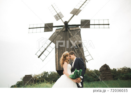 Stylish couple of happy newlyweds walking in the park on their wedding day with bouquet Stylish couple of happy newlyweds walking in the park on their wedding day with bouquet 72036035