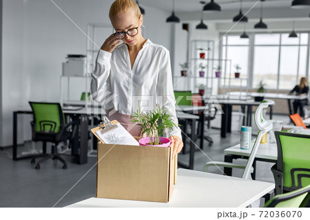 sad dismissed female worker is taking her office supplies from office 72036070