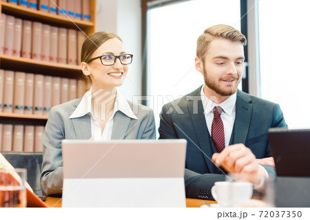 Young attorneys in law firm giving overview on case in partner meeting Young attorneys in law firm giving overview on case in partner meeting 72037350