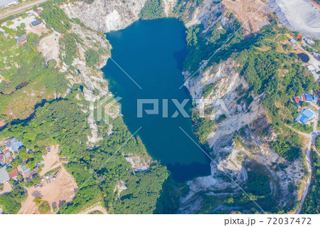 Aerial view of Grand Canyon Chonburi. Trucks dig coal mining or ore with black grunge ground in quarry with mountain hills. Nature landscape background in factory industry. Environment resources. 72037472