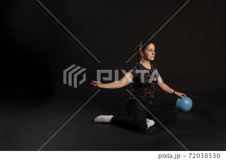 Fitness girl with Aqua ball, pulls the leg. Going in for sports on a black background Smiling with a lovely smile 72038530
