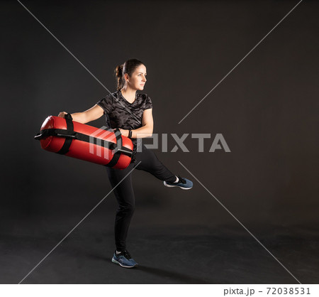 Fitness woman with Aqua Bag, sideways leg, moves. Engaged in sports on a black background Happy with beautiful eyes 72038531