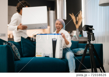 Happy videobloggers record unpacking video for their video blog with a brand new gaming console at home. 72038626