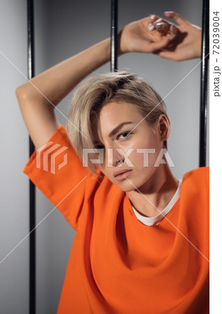 A close-up portrait of an orange-robed prisoner in prison against the background of prison bars 72039004