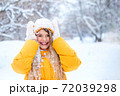 Outdoor portrait of young smiling girl, wearing yellow jacket in winter park 72039298
