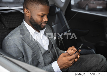 Closeup of african american entrepreneur using mobile phone in car 72039450
