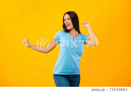 Smiling woman enjoying music and dancing at yellow studio Smiling woman enjoying music and dancing at yellow studio 72039665