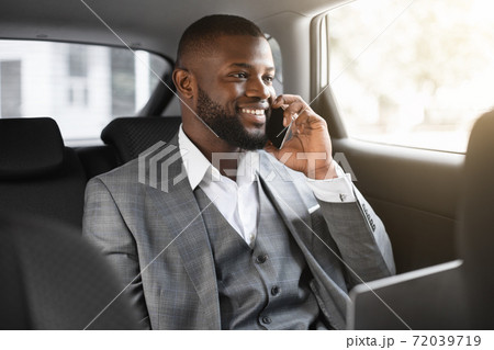 Happy black businessman talking on mobile phone in car 72039719