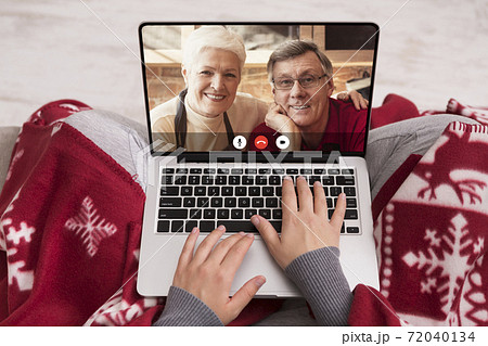 Woman Calling Senior Parents On Christmas Sitting With Laptop Indoor 72040134