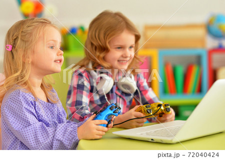 Two pretty little girls lying playing video game Two pretty little girls lying playing video game 72040424