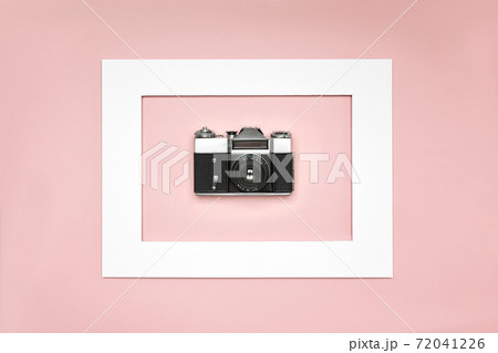 Flat lay old analog camera in the paper frame on pink background 72041226