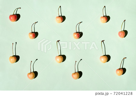 Yellow and pink cherries pattern on green background flat lay 72041228