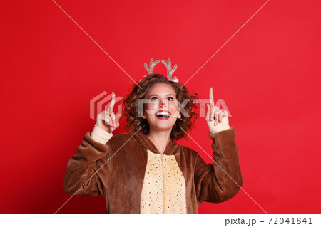 Funny female  in reindeer costume smiling and pointing up 72041841