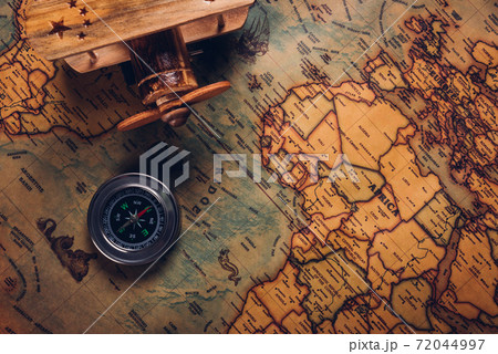 Old compass discovery and wooden plane on vintage paper antique world map 72044997