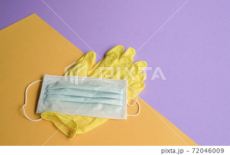 Hand gloves and medical face mask on purple and yellow background. Hand gloves and medical face mask on purple and yellow background. 72046009