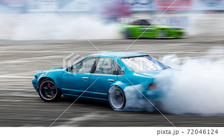 Blurred car drifting, Two car drifting battle on asphalt street road race track, Automobile and automotive drift car with smoke from burning tire on speed track. Blurred car drifting, Two car drifting battle on asphalt street road race track, Automobile and automotive drift car with smoke from burning tire on speed track. 72046124