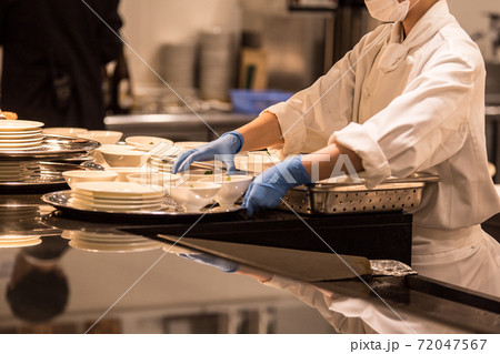 手袋とマスクをつけてキッチンで仕事をする人の画像 72047567