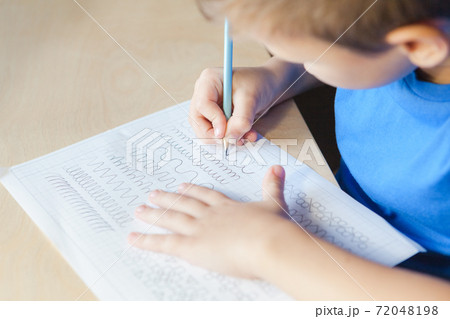 Close up of cute boy tracing lines with pencil 72048198