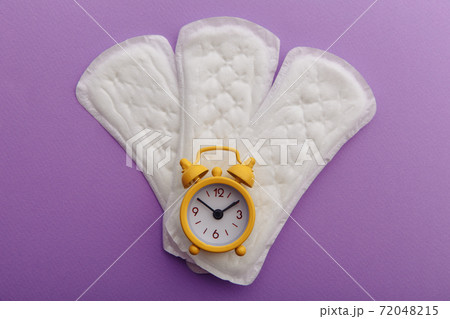 Menstrual pads and yellow alarm clock on lilac background. Female's menstrual cycle concept Menstrual pads and yellow alarm clock on lilac background. Female's menstrual cycle concept 72048215