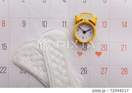 Calendar, menstrual pads and yellow alarm clock 72048217