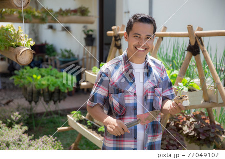 man with small plant in his farm 72049102