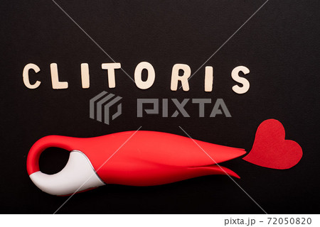 Top view of a clitoral vibrator in the form of a red tulip, a heart and the inscription clitoris on a black background Top view of a clitoral vibrator in the form of a red tulip, a heart and the inscription clitoris on a black background 72050820
