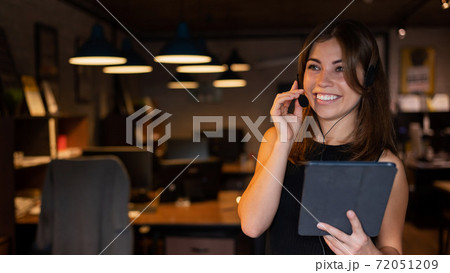 Beautiful business woman wearing in a headset is holding a digital tablet in the office 72051209