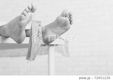 Feet of a dead woman in a morgue with a mask. Victim of the coronavirus epidemic. Feet of a dead woman in a morgue with a mask. Victim of the coronavirus epidemic. 72051220