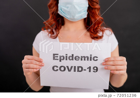 A faceless redhead woman in a medical mask holds an announcement about the epidemic of coronavirus. Quarantine. Pandemic covid-19. A faceless redhead woman in a medical mask holds an announcement about the epidemic of coronavirus. Quarantine. Pandemic covid-19. 72051236