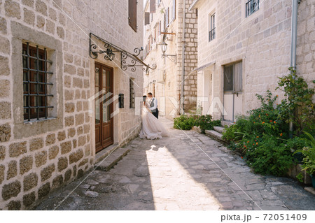 Wedding couple on the street of the old city, among ancient houses. Fine-art wedding photo in Montenegro, Perast. Wedding couple on the street of the old city, among ancient houses. Fine-art wedding photo in Montenegro, Perast. 72051409