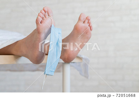 Close-up of dead men feet in a morgue with a medical mask on a toe. An unrecognizable woman has died from the coronavirus Close-up of dead men feet in a morgue with a medical mask on a toe. An unrecognizable woman has died from the coronavirus 72051668