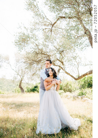 the groom gently hugs the bride from behind in the olive grove 72052057