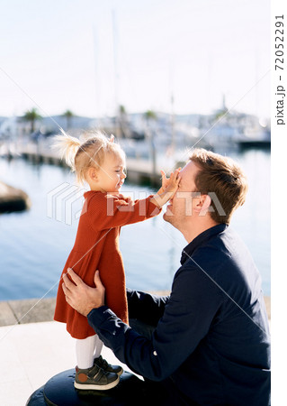 Little girl is playing peek-a-boo with her daddy on a boat marina 72052291