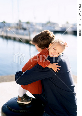 Father and daughter are hugging on a boat pier while having a family day 72052408