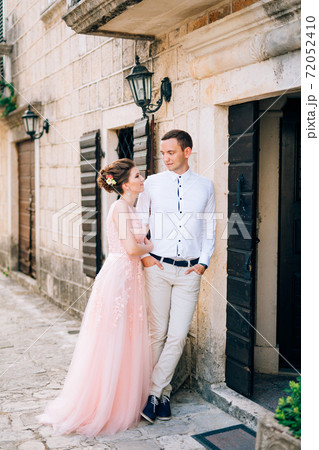 bride and groom stand hugging next to the ancient house 72052410